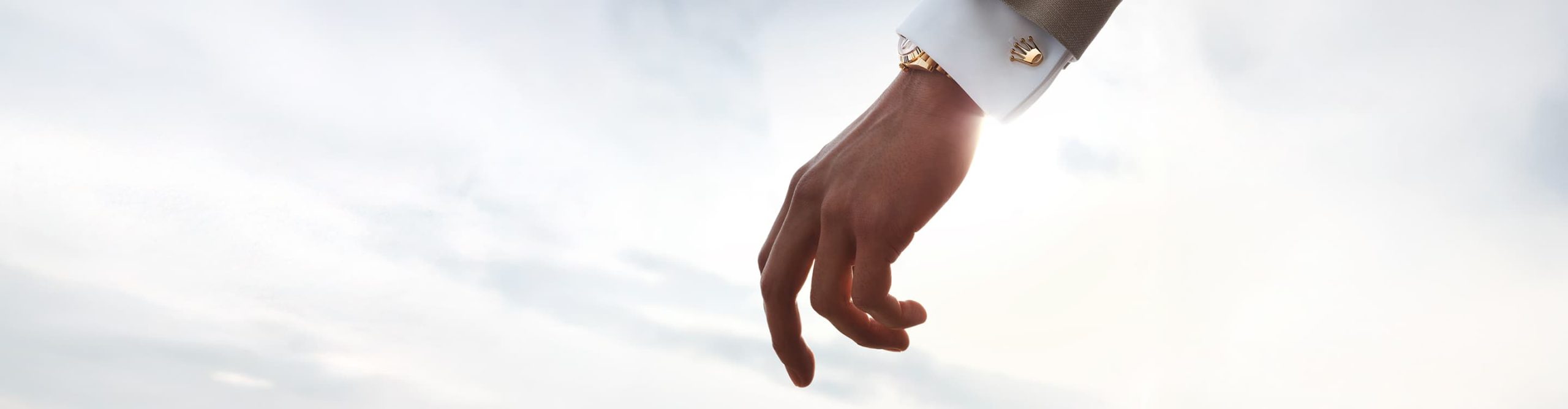 Image of a model wearing Rolex 'Crown' cufflinks in 18ct yellow gold with a matching gold Rolex Watch. Rolex Accessories - DAFC