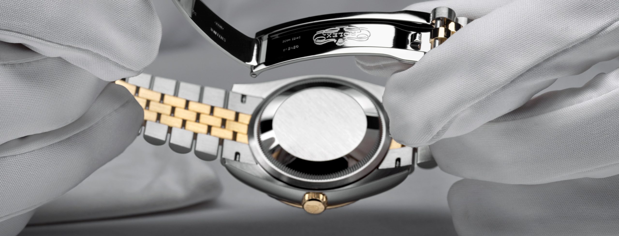 Gloved hands inspecting a Rolex case and bracelet during servicing.