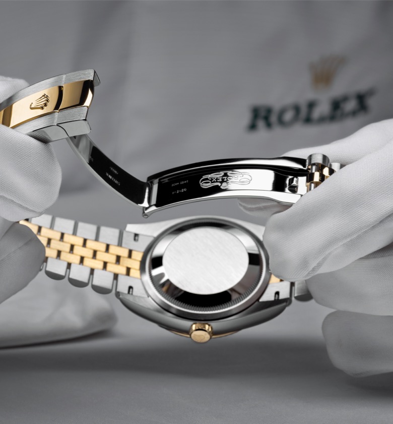 Gloved hands inspecting a Rolex case and bracelet during servicing.