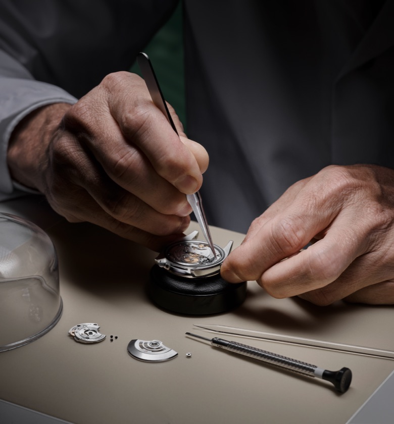 A Rolex watchmaker meticulously servicing a movement.