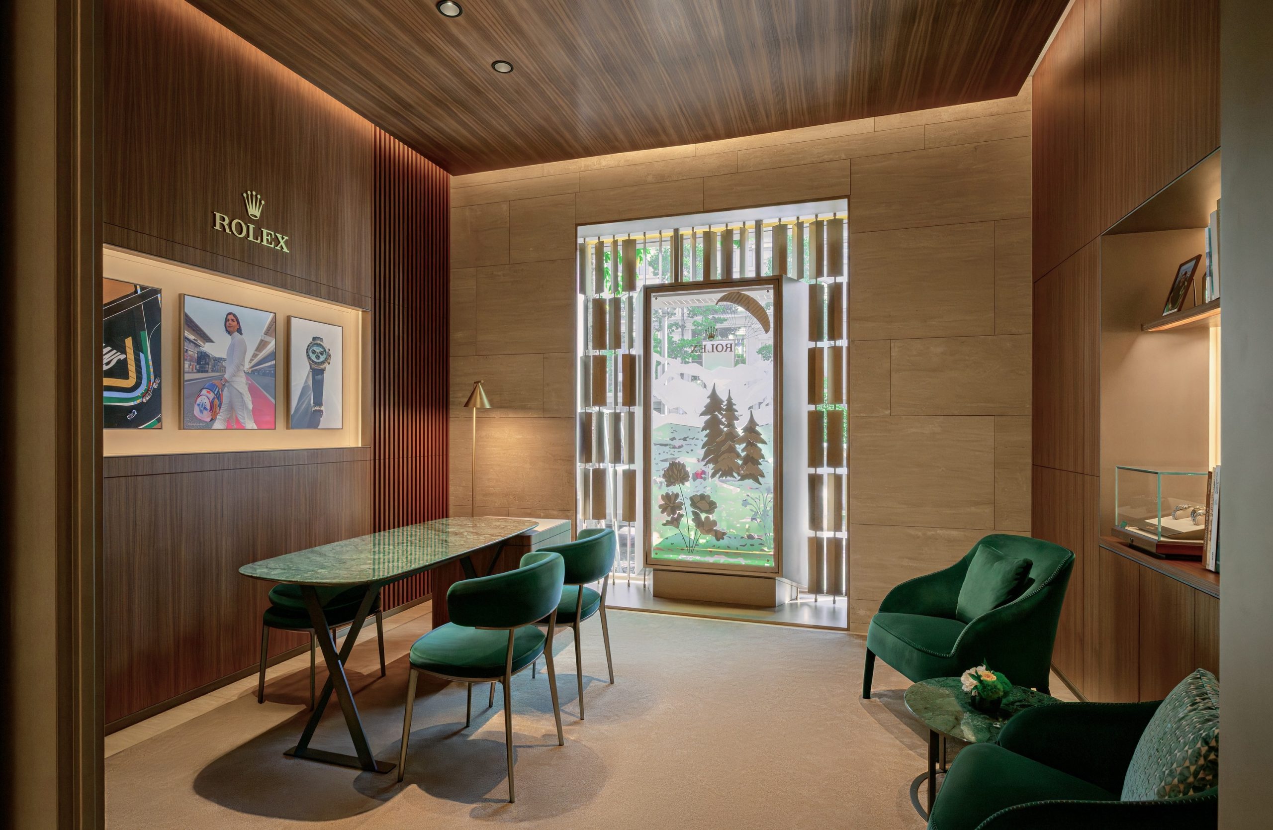 Interior of DAFC Rolex boutique in Vietnam featuring a consultation area with green velvet chairs, display case with luxury watches, and natural light from a decorative window.